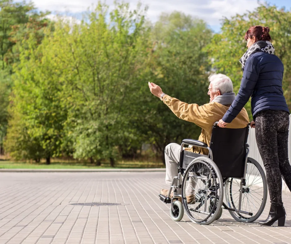 Speedy Care support worker assisting an NDIS participant in a wheelchair on a park walk in Melbourne